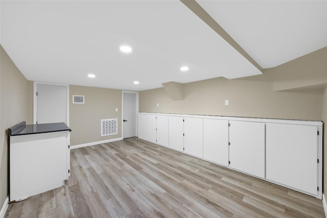 finished below grade area with visible vents, recessed lighting, and light wood-style flooring