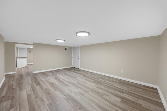 finished basement featuring baseboards, visible vents, and light wood-style flooring