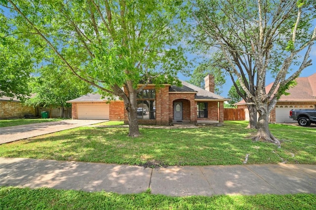 view of front facade featuring a chimney, brick siding, fence, a front yard, and concrete driveway