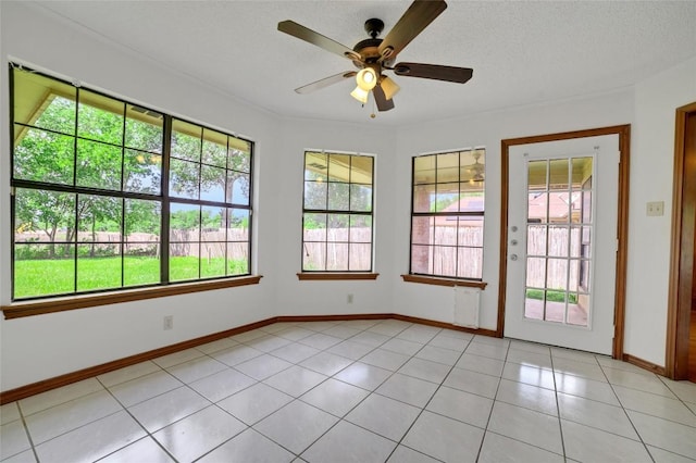 spare room with light tile patterned flooring, ceiling fan, baseboards, and a healthy amount of sunlight