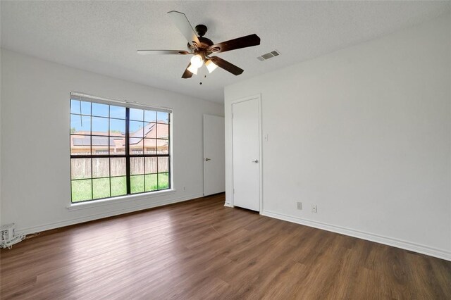 empty room featuring baseboards, visible vents, wood finished floors, and ceiling fan