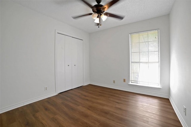 unfurnished bedroom featuring baseboards, ceiling fan, dark wood-style flooring, and a closet