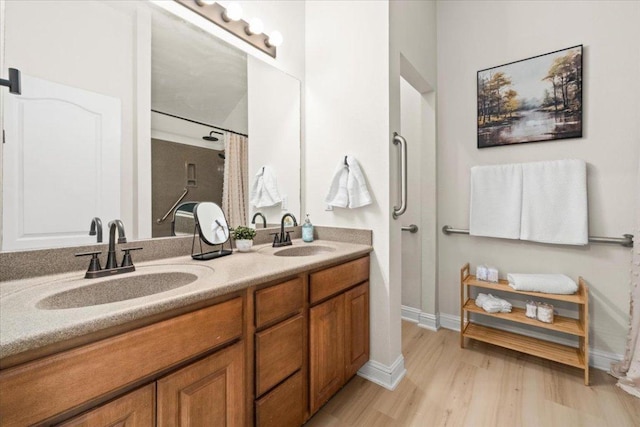 231 Skinner, Kyle, TX 78640 - bathroom with wood finished floors, double vanity, baseboards, and a shower with shower curtain