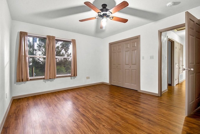 unfurnished bedroom featuring baseboards, wood finished floors, and a closet
