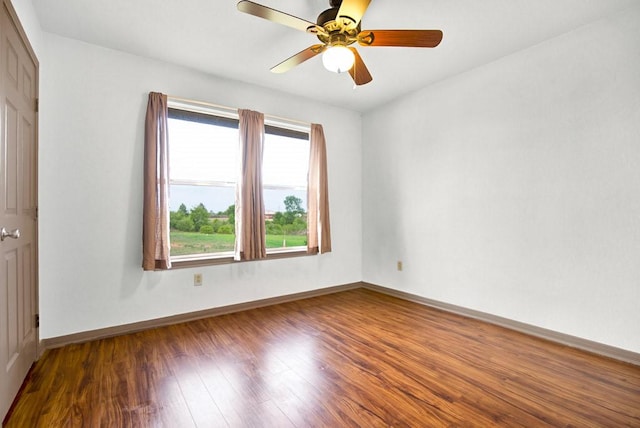 empty room with a ceiling fan, wood finished floors, and baseboards