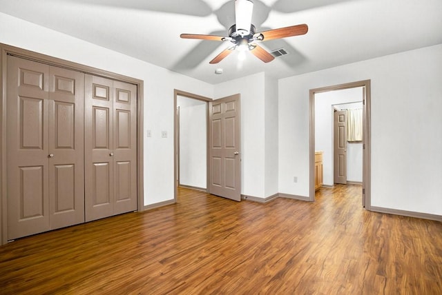 unfurnished bedroom featuring baseboards, visible vents, wood finished floors, and a closet