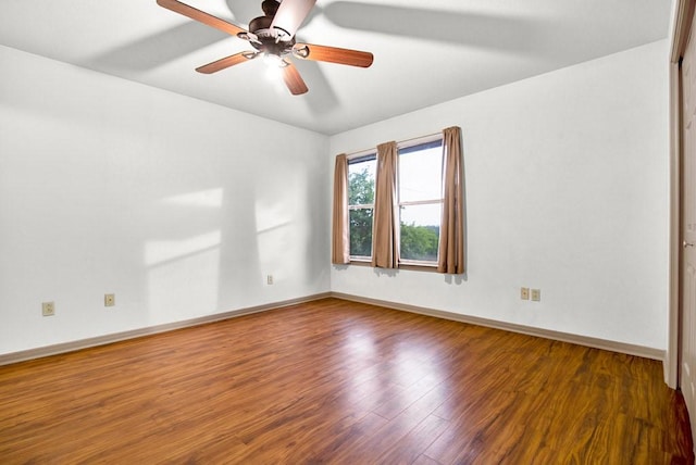 empty room featuring baseboards, wood finished floors, and a ceiling fan