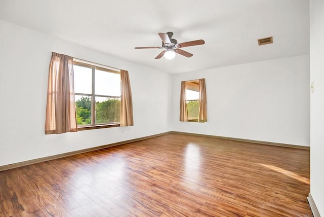 spare room featuring wood finished floors, a healthy amount of sunlight, and visible vents