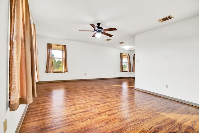 unfurnished room featuring baseboards, visible vents, wood finished floors, and ceiling fan