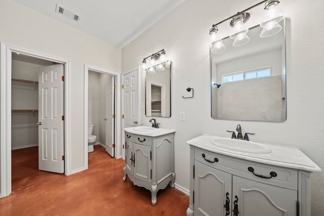 bathroom featuring visible vents, two vanities, concrete flooring, and a sink