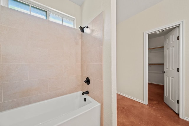 bathroom featuring shower / tub combination, a spacious closet, and baseboards