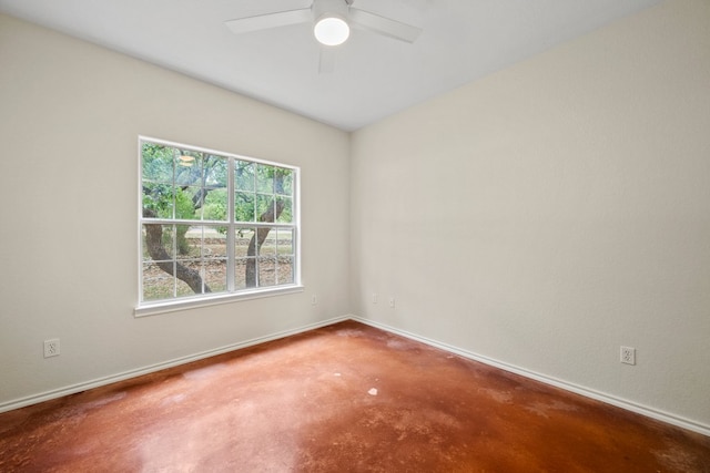 spare room with a ceiling fan, concrete flooring, and baseboards