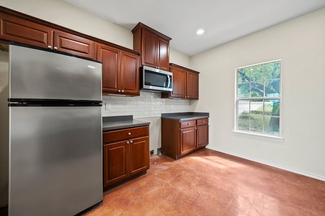 kitchen with finished concrete flooring, decorative backsplash, dark countertops, stainless steel appliances, and baseboards