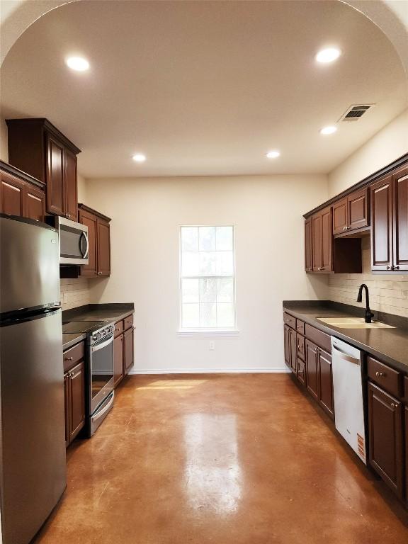 1159 Stallion Springs Dr, Fischer, TX 78623 - kitchen featuring stainless steel appliances, a sink, dark countertops, decorative backsplash, and dark brown cabinetry