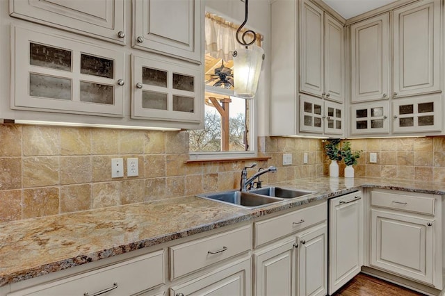 kitchen with glass insert cabinets, dishwasher, decorative backsplash, and a sink