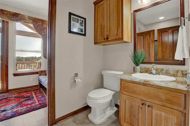 bathroom featuring toilet, ensuite bathroom, vanity, and baseboards