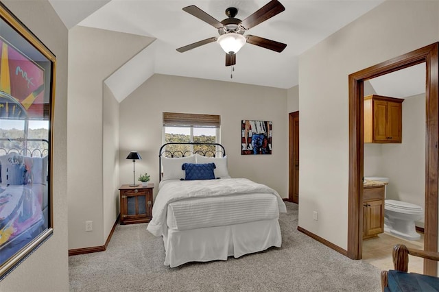bedroom with ceiling fan, baseboards, light colored carpet, and ensuite bathroom