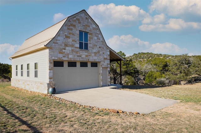 view of side of home featuring a garage, metal roof, an outdoor structure, a yard, and stone siding