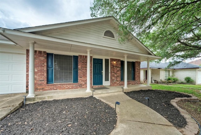 view of front of house with an attached garage, covered porch, and brick siding