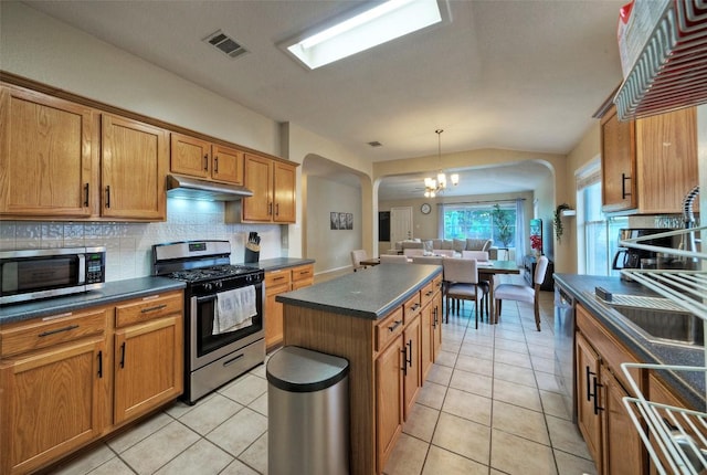 kitchen featuring tasteful backsplash, stainless steel appliances, dark countertops, visible vents, and a notable chandelier