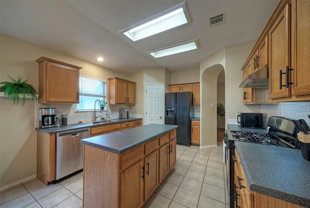 kitchen featuring a sink, visible vents, dark countertops, under cabinet range hood, and black appliances