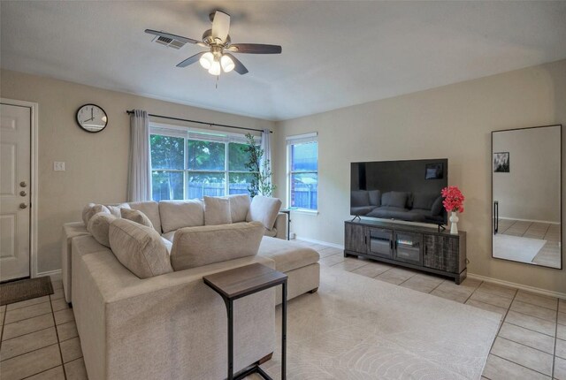 living area featuring light tile patterned floors, visible vents, ceiling fan, and baseboards