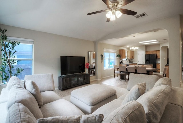 living room with visible vents, arched walkways, ceiling fan with notable chandelier, and light tile patterned floors