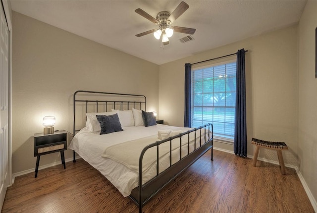 bedroom with wood finished floors, ceiling fan, visible vents, and baseboards