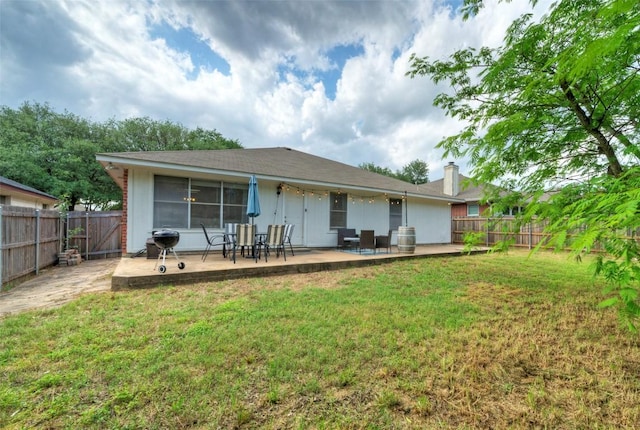 rear view of house featuring a chimney, a yard, a patio, and a fenced backyard