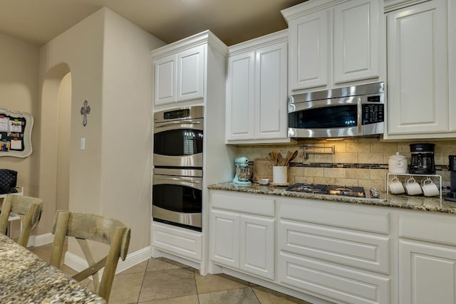 2600 Dalea St, Round Rock, TX 78681 - kitchen featuring stainless steel appliances, tasteful backsplash, white cabinetry, arched walkways, and stone countertops