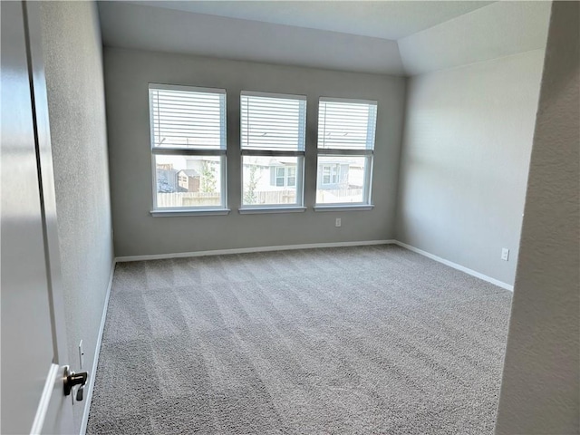 unfurnished room featuring lofted ceiling, carpet, and baseboards