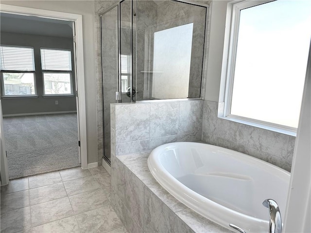 bathroom featuring baseboards, a shower stall, a wealth of natural light, and a bath