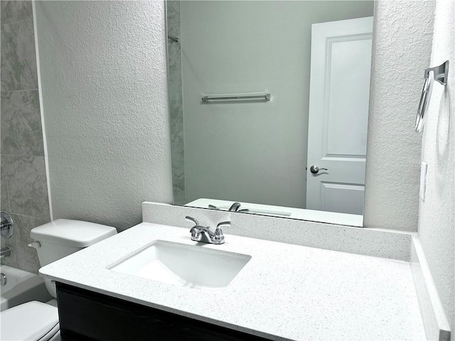 full bathroom with bathing tub / shower combination, toilet, a textured wall, and vanity