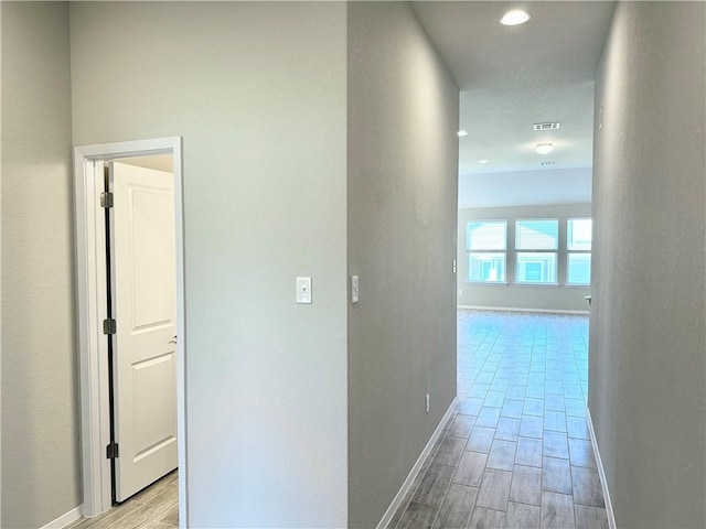 corridor featuring wood tiled floor, recessed lighting, and baseboards