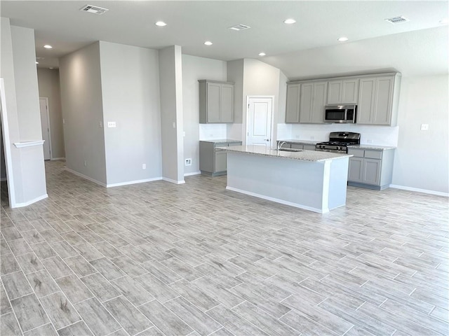kitchen featuring a sink, stainless steel appliances, visible vents, baseboards, and gray cabinetry