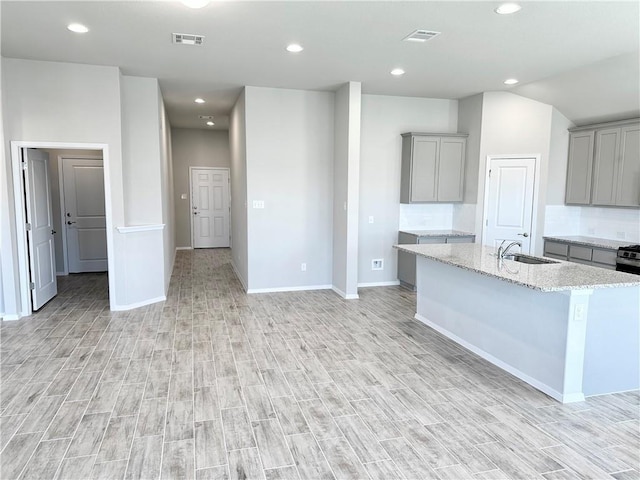 kitchen featuring light wood-style floors, gray cabinetry, baseboards, and a sink