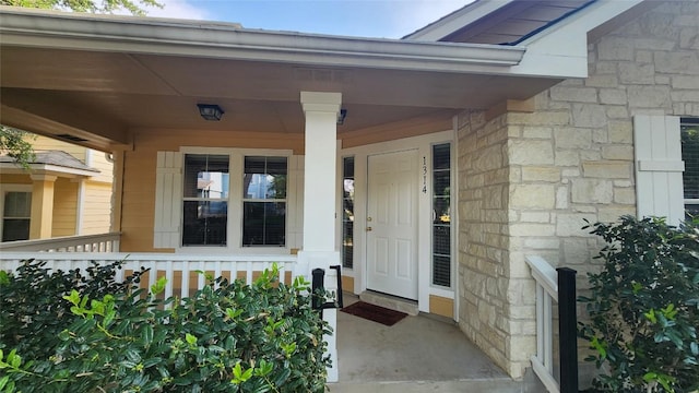 entrance to property featuring a porch and stone siding