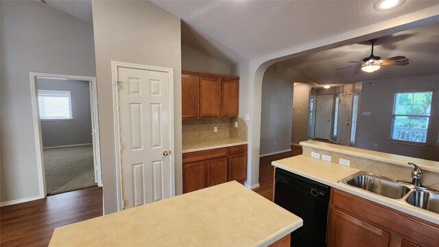 kitchen with lofted ceiling, a sink, light countertops, dark wood-style floors, and black dishwasher