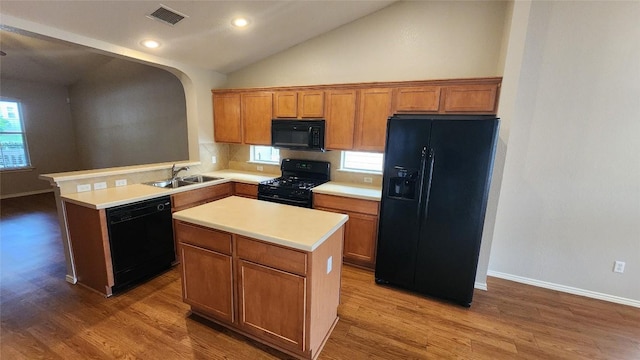 kitchen featuring brown cabinets, a sink, visible vents, light countertops, and black appliances