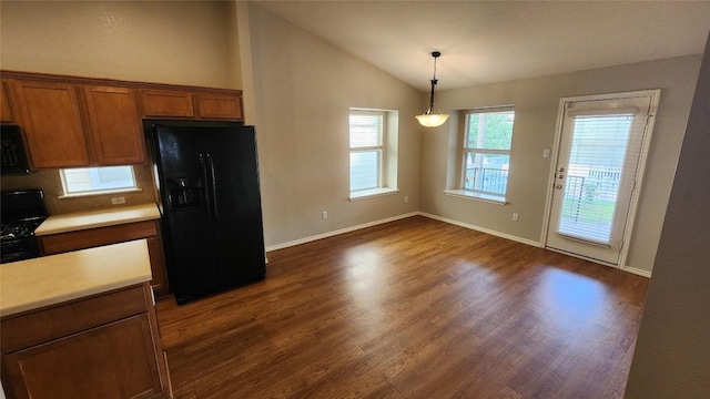 kitchen featuring brown cabinets, light countertops, black appliances, vaulted ceiling, and dark wood-type flooring