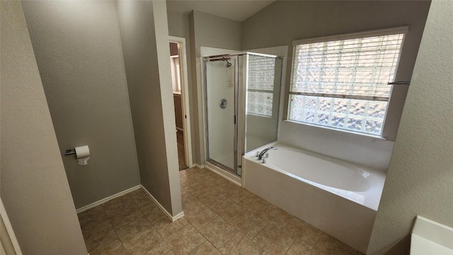 bathroom featuring tile patterned flooring, a bath, a textured wall, baseboards, and a stall shower