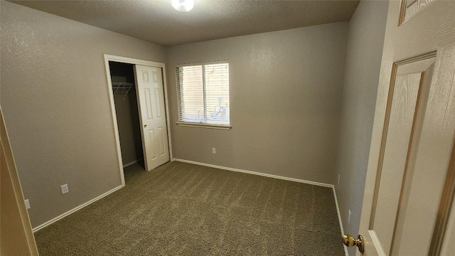 unfurnished bedroom featuring a closet, a textured wall, baseboards, dark carpet, and a textured ceiling