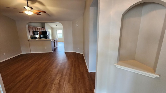 hallway with arched walkways, baseboards, and dark wood-type flooring