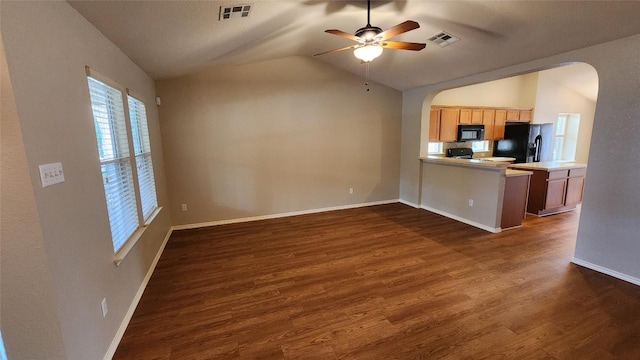 kitchen featuring arched walkways, black appliances, dark wood-style flooring, a peninsula, and lofted ceiling