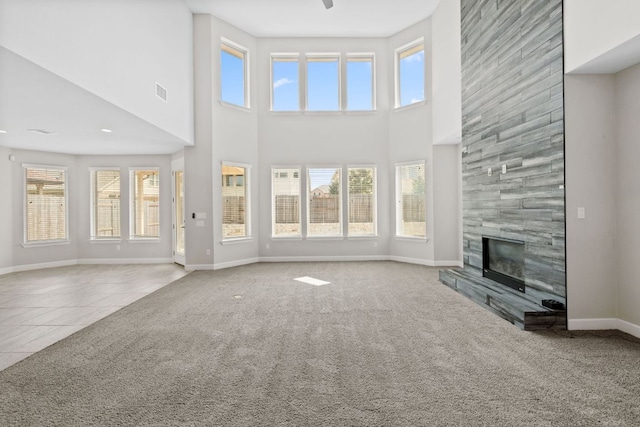 829 Expedition Way, Round Rock, TX 78665 - unfurnished living room featuring a towering ceiling, plenty of natural light, a fireplace, carpet, and tile patterned flooring