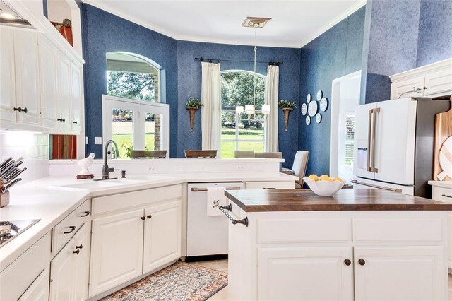93 Duck Lake Dr, Lakeway, TX 78734 - kitchen featuring white appliances, a sink, a peninsula, wallpapered walls, and crown molding