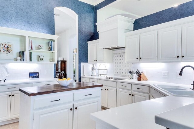 93 Duck Lake Dr, Lakeway, TX 78734 - kitchen featuring butcher block countertops, a sink, arched walkways, tasteful backsplash, and black electric stovetop
