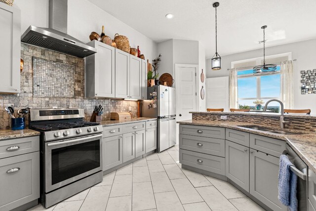 101 Durango Dr, Johnson City, TX 78636 - kitchen with a sink, decorative backsplash, wall chimney range hood, gray cabinetry, and appliances with stainless steel finishes