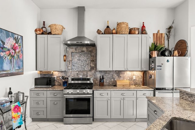101 Durango Dr, Johnson City, TX 78636 - kitchen with wall chimney exhaust hood, light stone countertops, gray cabinets, and appliances with stainless steel finishes