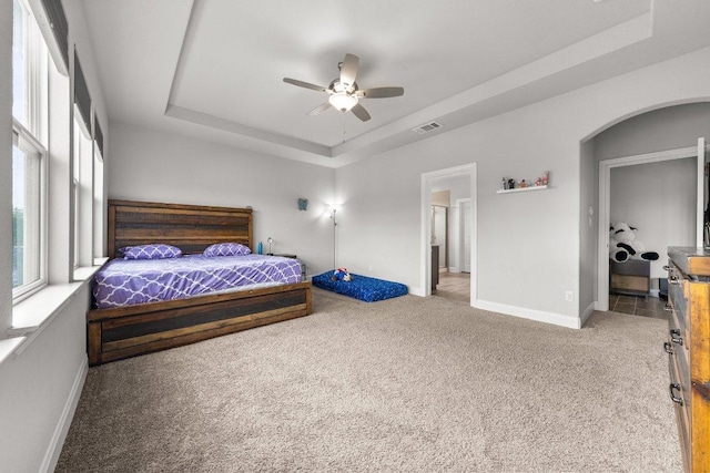 3750 E Palm Valley Blvd Unit 98, Round Rock, TX 78665 - carpeted bedroom with arched walkways, baseboards, visible vents, a ceiling fan, and a tray ceiling